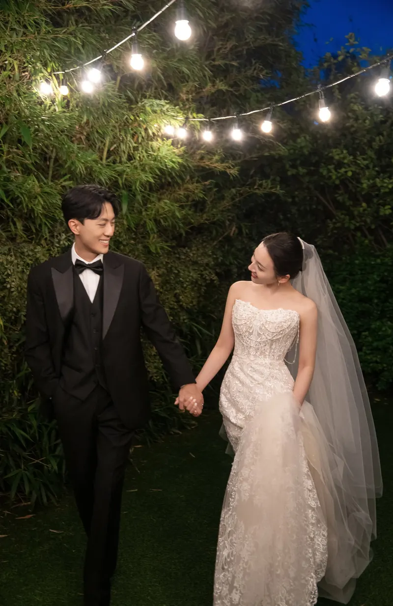 야외 조명 아래 손을 잡은 신랑 신부